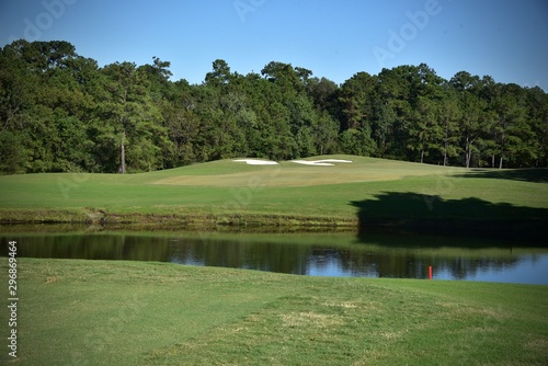 Golf course landscape, including a water hazard, sand traps and putting green on a beautiful sunny day.