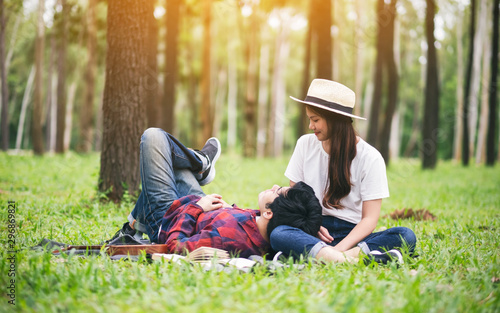 A young asian lover couple sitting and lying down together in the park