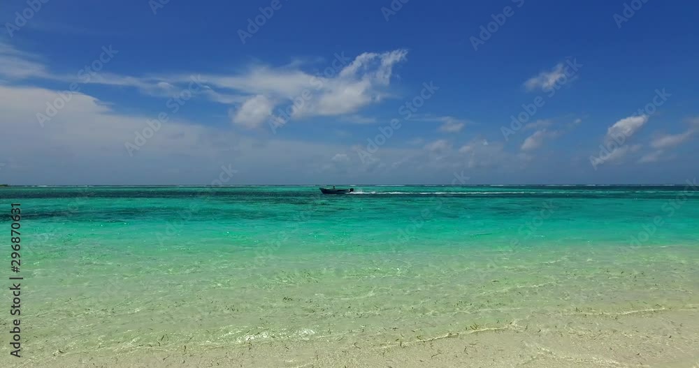 Speed boat sailing on a turquoise narrow horizon line separating white beach from blue sky in Caribbean Speed boat sailing on a turquoise narrow horizon line separating white beach from blue sky in Caribbean