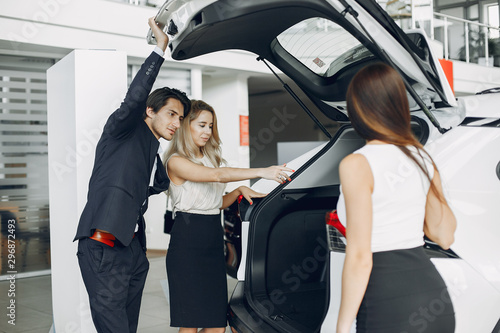People in a car salon. Man buying the car. Elegant women with handsome man © prostooleh