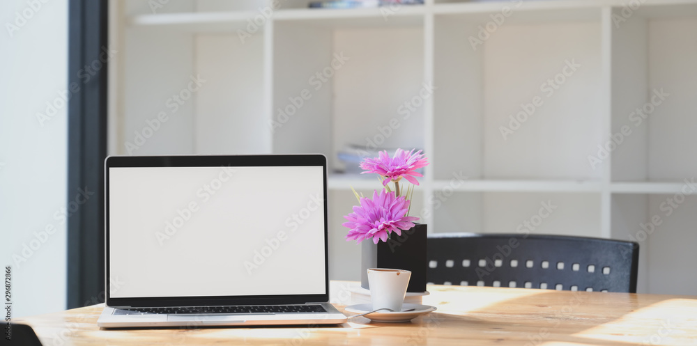 Open blank screen laptop computer in comfortable workspace with pink flower Open blank screen laptop computer in comfortable workspace with pink flower