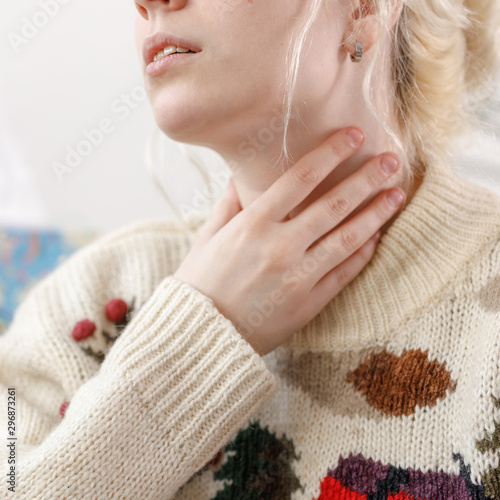 The girl in the sweater is sick. Colds and flu. The patient caught a cold  feeling sick. Unhealthy girl with a sore throat. Square.