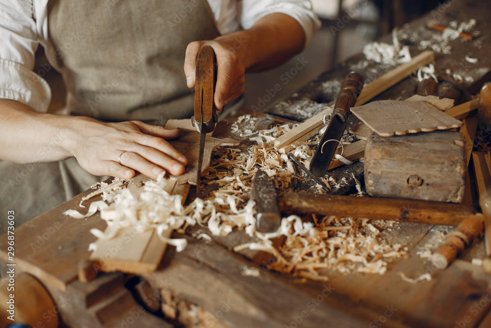 Man working with a wood. Carpenter in a white shirt Man working with a wood. Carpenter in a white shirt