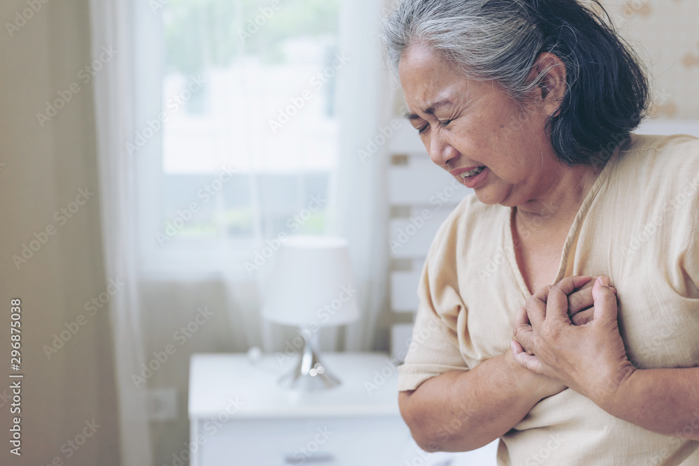 Senior female Asian suffering from bad pain in his chest heart attack at home - senior heart disease Senior female Asian suffering from bad pain in his chest heart attack at home - senior heart disease