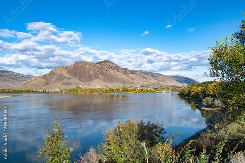 View on Mount Paul and confluence of Thompson Rivers, Overlanders Beach in Kamloops, BC. Sunny autumn day, clouds reflecting in the water.