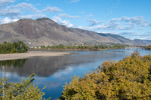 View on Mount Paul and confluence of Thompson Rivers, Overlanders Beach in Kamloops, BC. Sunny autumn day, clouds reflecting in the water.
