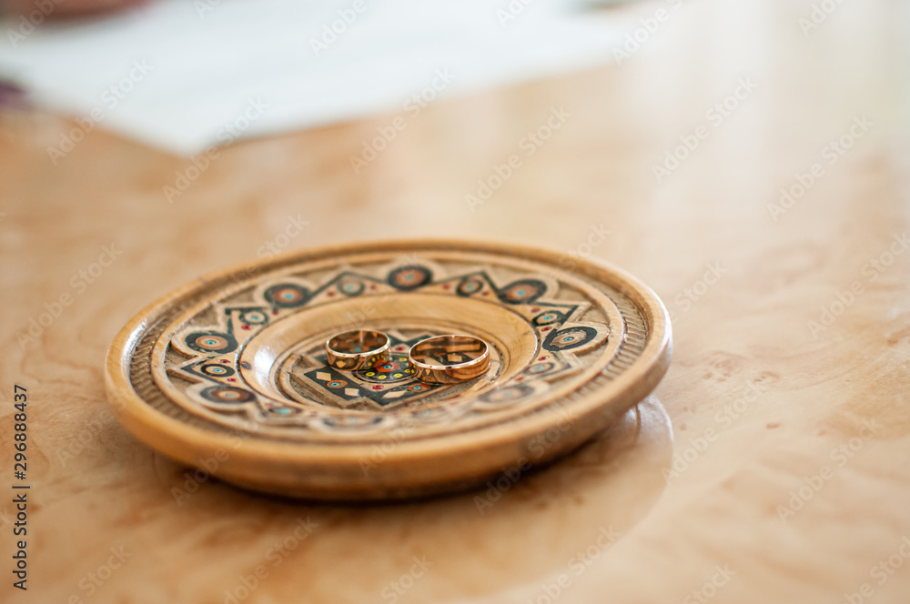 Pair of gold wedding rings on the wooden plate Pair of gold wedding rings on the wooden plate