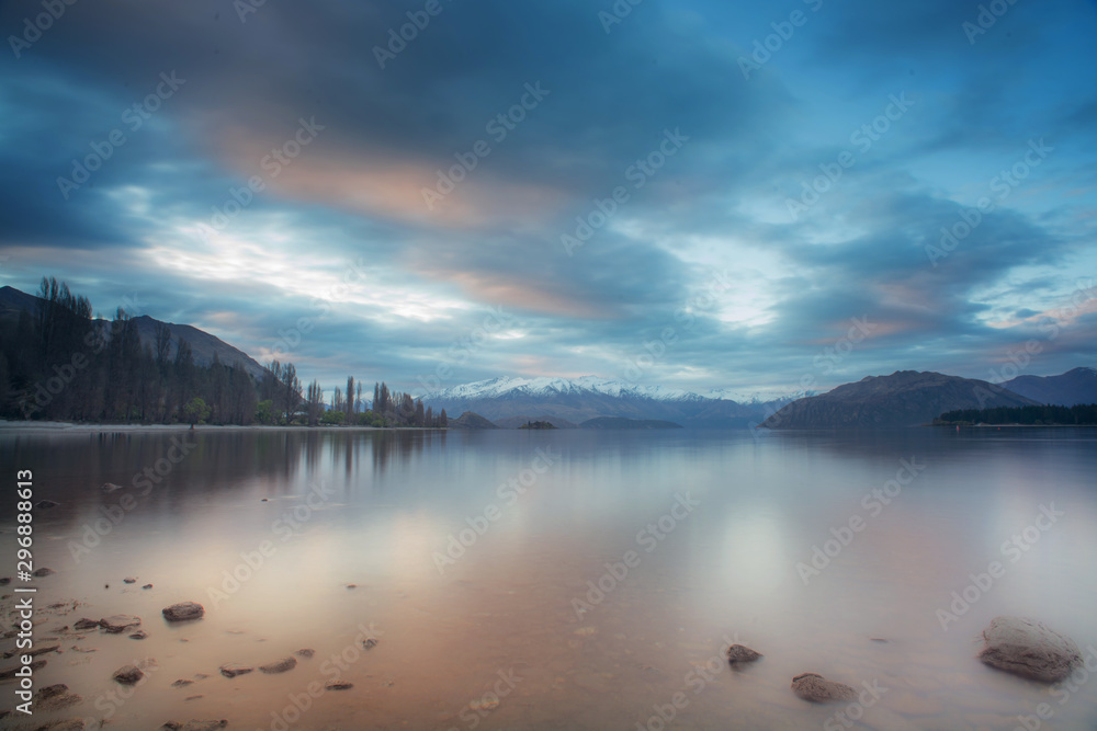 Lake wanaka during sunset in long exposure shot with snowcap mountain in the background.New Zealand road trip.