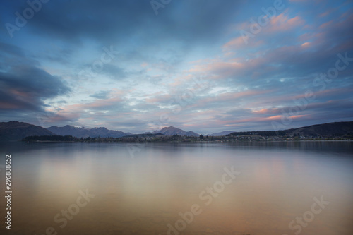 Lake wanaka during sunset in long exposure shot with snowcap mountain in the background.New Zealand road trip.