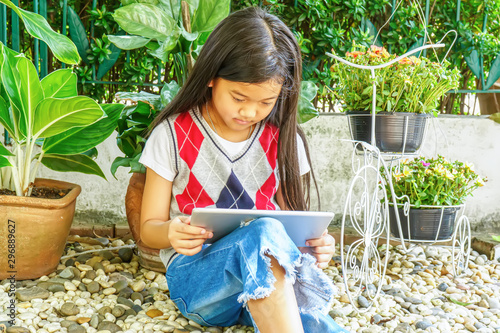 The girl sitting in mini garden with playing tablet pc.