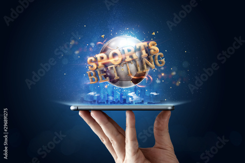 Smartphone in hand a gold inscription Sports Betting with a 3D soccer ball on a blue background. Bets, sports betting, bookmaker. Mixed media photo