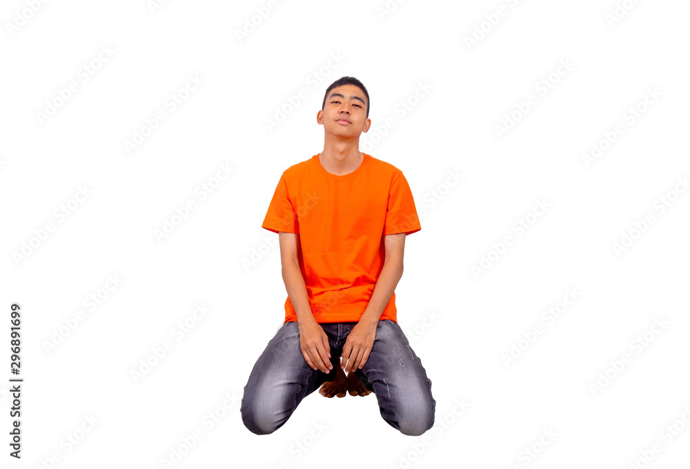A teenage boy in orange t shirt is kneeling in the studio and look into the camera