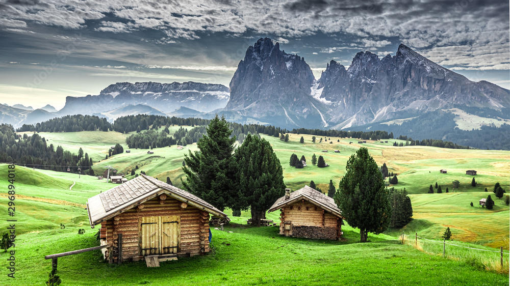 Fototapeta premium Small wooden huts at sunrise in Alpe di Siusi, Dolomites
