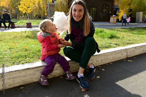 Little beautiful girl with expressive face eats cotton candy in the park
