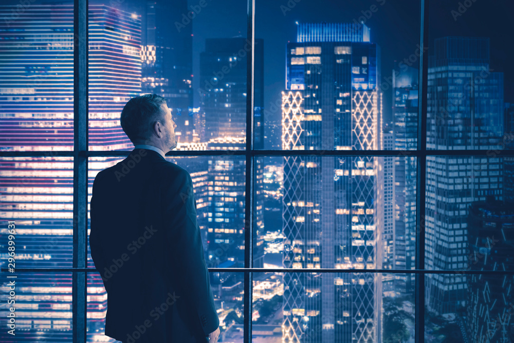 Fototapeta premium Male manager looking at night city in the office