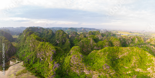 Epic aerial view of Ninh Binh region, Trang An Tam Coc tourist attraction, UNESCO World Heritage Site, Scenic river crawling through karst mountain ranges in Vietnam, travel destination.