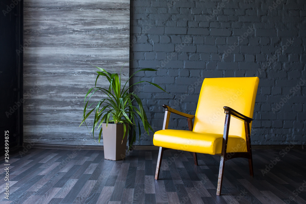 Stylish retro yellow chair in the gray room. Brick gray wall. Room. - obrazy, fototapety, plakaty 