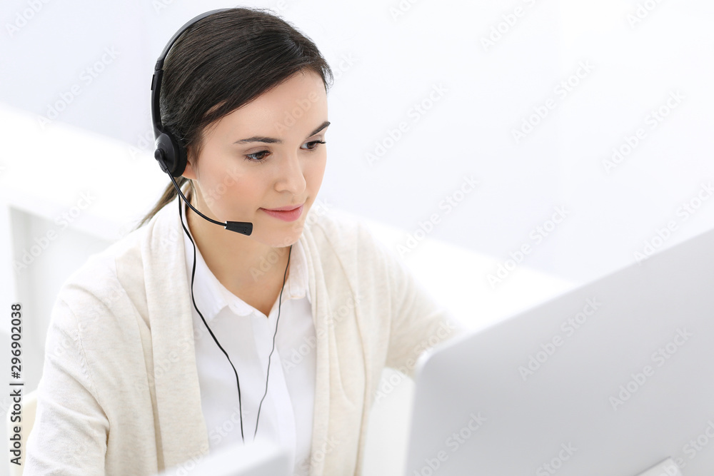 Call center. Beautiful woman receptionist sitting in headset at customer service office. Group of operators at work. Business concept Call center. Beautiful woman receptionist sitting in headset at customer service office. Group of operators at work. Business concept