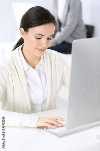 Business woman working with computer in office, female colleague at background. Headshot of Lawyer or accountant at work while sitting at the desk