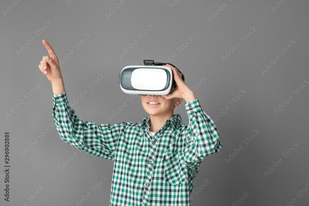 Freestyle. Boy in virtual reality headset standing isolated on grey wall pointing at space aside excited Freestyle. Boy in virtual reality headset standing isolated on grey wall pointing at space aside excited