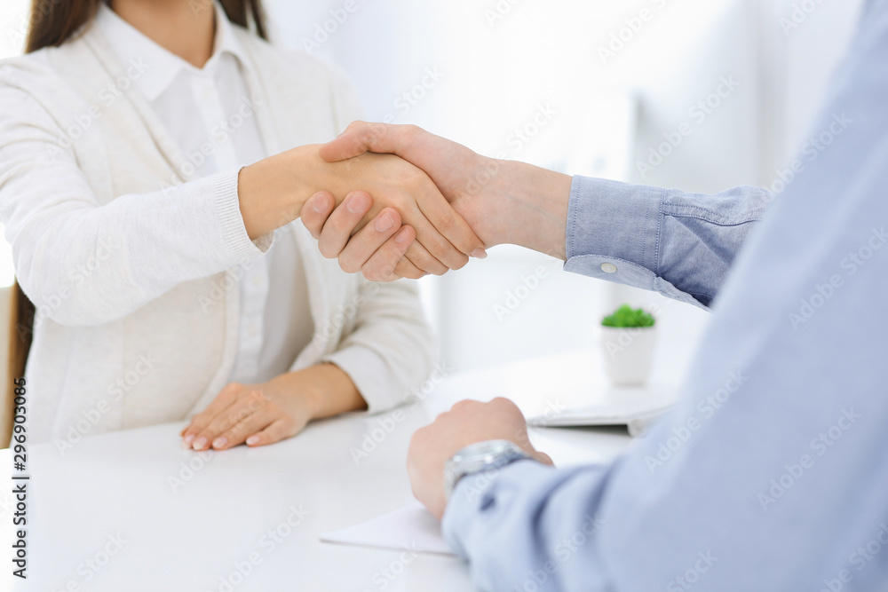 Obraz premium Business people shaking hands at meeting or negotiation. Businessman and woman handshake at office while sitting at the desk. Success concept
