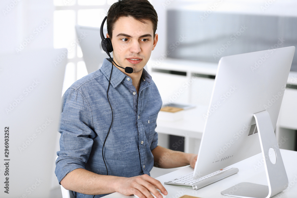 Group of operators at work. Call center. Focus on young man receptionist in headset at customer service. Business concept and casual clothing style Group of operators at work. Call center. Focus on young man receptionist in headset at customer service. Business concept and casual clothing style