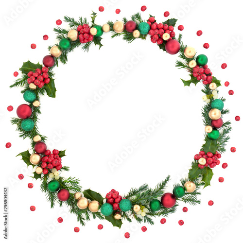 Christmas wreath abstract decoration with winter flora, baubles and loose holly berries on white background with copy space. Decorative symbol for the festive season.