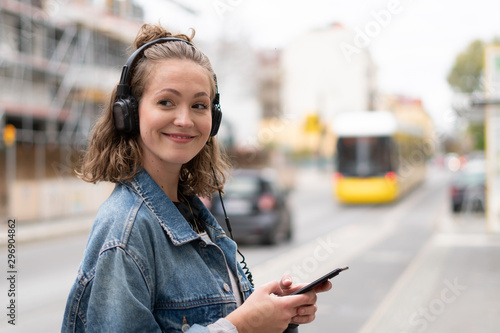 Girl with headphones listening to music waiting for the streetcar
