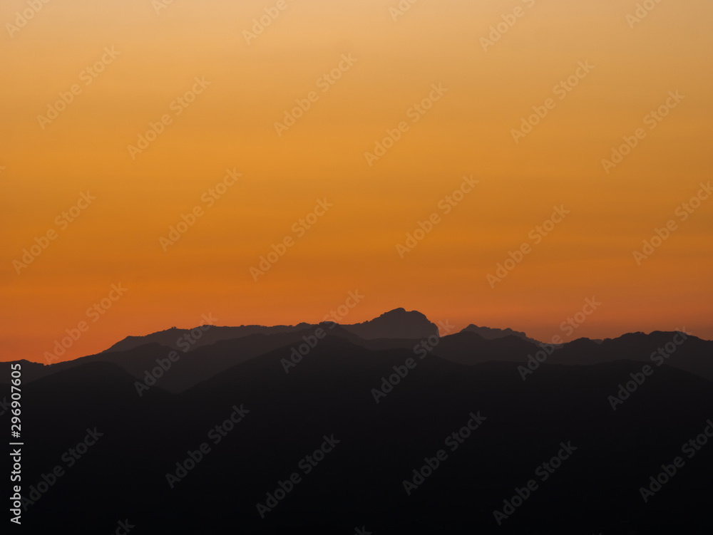 silhouettes of mountains at sunset with high orange contrast