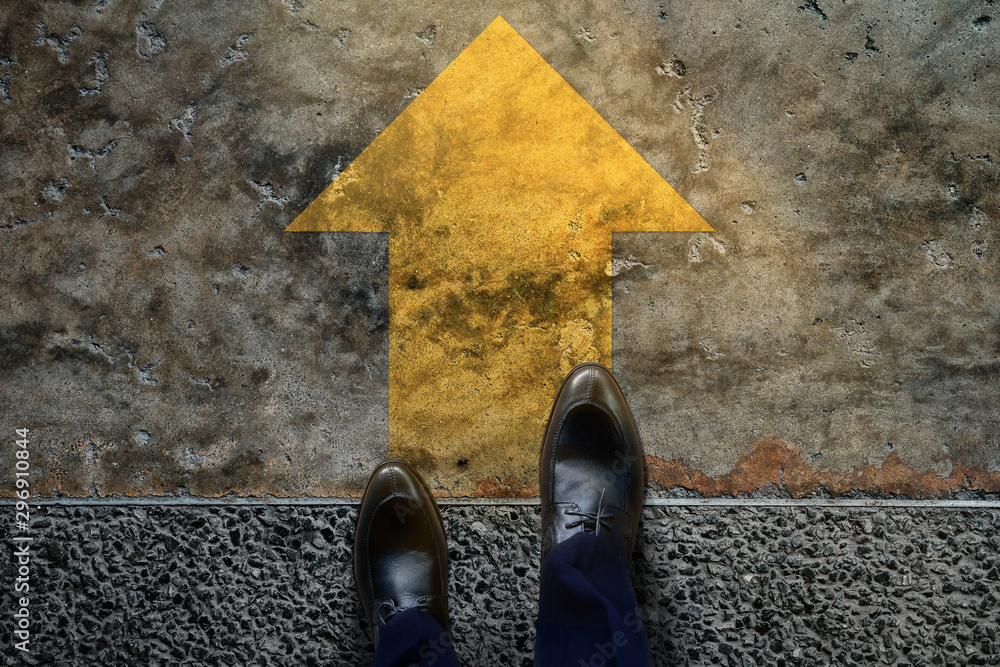 Start and Challenge Concept. a Business Man on Formal Shoes Steps to Follow a Yellow Arrow, Get Ready to Moving Forward or take a Chance to Success. Top View - obrazy, fototapety, plakaty 