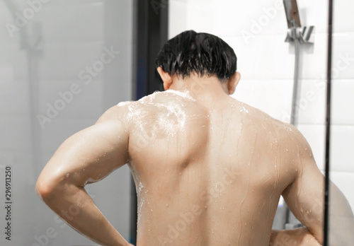 Closeup handsome asian man taking a shower in the bathroom, selective focus