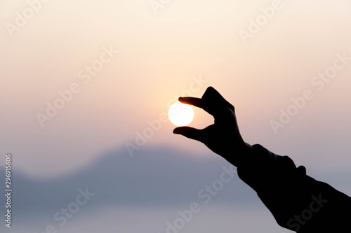 Closeup silhouette of woman hand holding sun rise in the morning, tourism concept