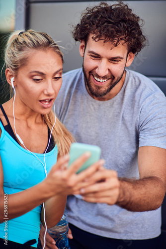 Modern woman and man jogging   exercising in urban surroundings and using cellphone at a pause   break.