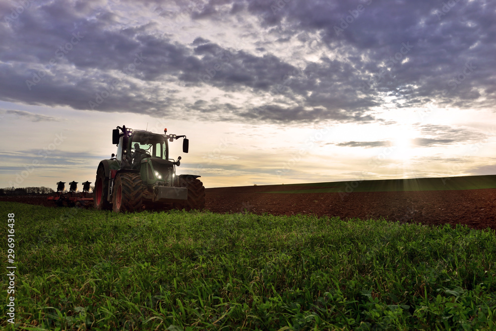 Fototapeta premium farmer plowing his fields at dusk
