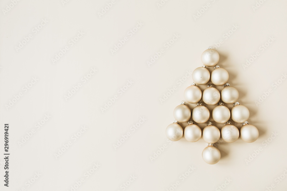 Christmas / New Year composition. Christmas tree symbol made of gold Christmas baubles on beige background. Flat lay, top view festive holiday concept. Christmas / New Year composition. Christmas tree symbol made of gold Christmas baubles on beige background. Flat lay, top view festive holiday concept.