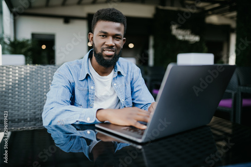 Portrait of a smiling african man with laptop at cafe