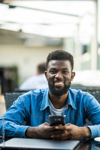 Portrait of African man use phone with laptop