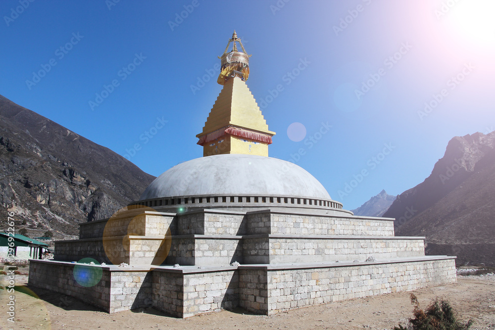 Old typical golden Buddhist stupa (chorten) near Thyangmoche village in Himalayas in Nepal with clear sky in the background. Above is a standard drawing of the eyes of Buddha.