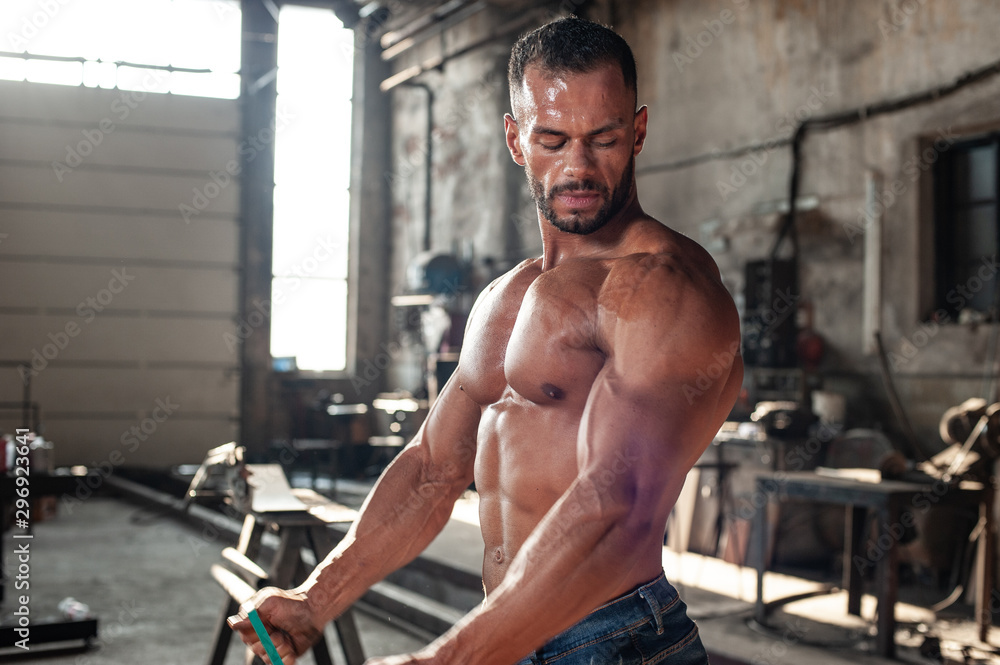 Obraz premium Muscled half naked man at work in an old factory.