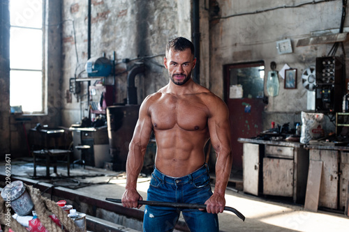 Muscled half naked man at work in an old factory.
