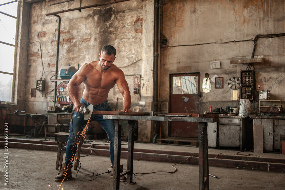 Muscled half naked man at work in an old factory. Stock-Foto Adobe Stock