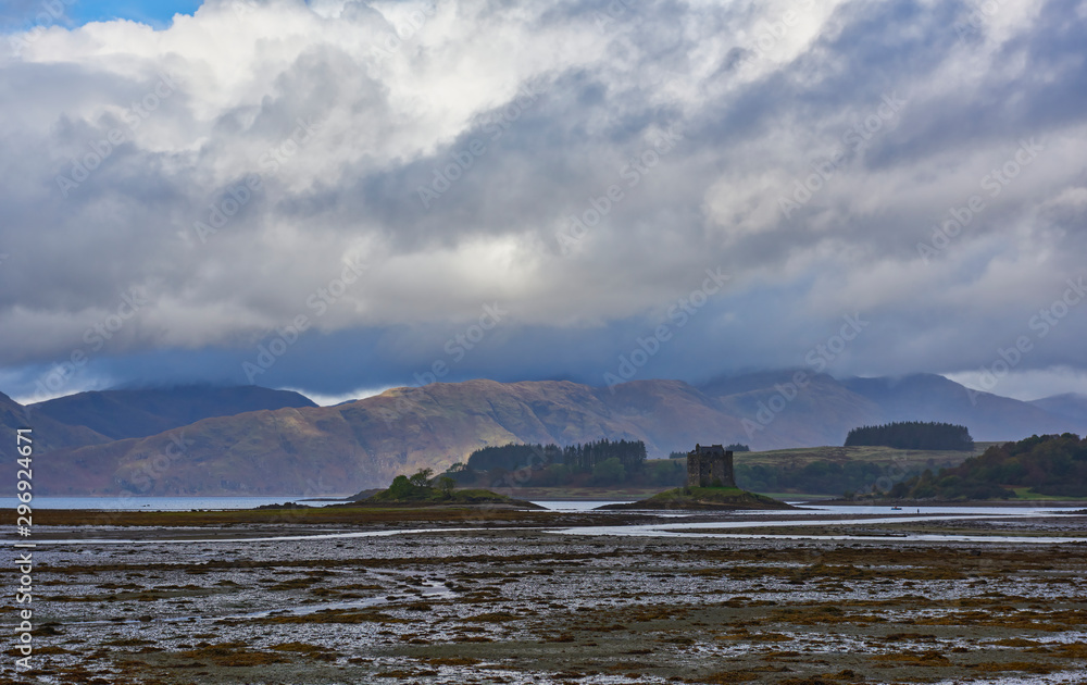 Castle Stalker perched on a small Island in Loch Linnhe on the Argyll coast of Scotland, with the mudflats exposed at low tide one gloomy afternoon.