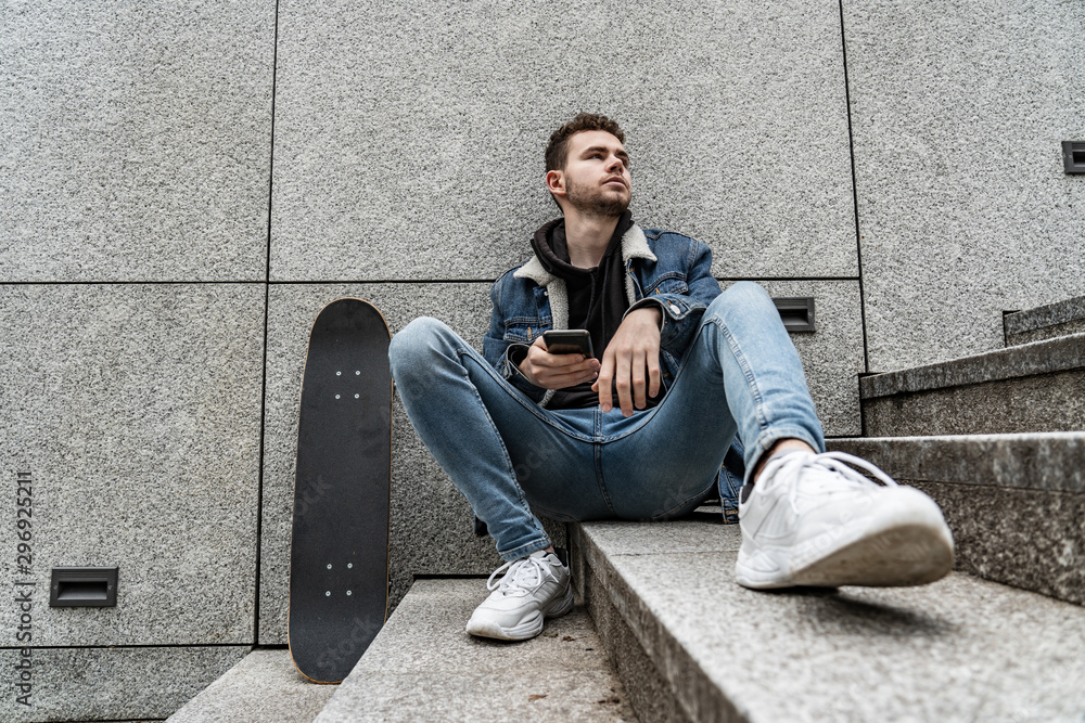 Young man sitting with saketeboard on stairs Young man sitting with saketeboard on stairs