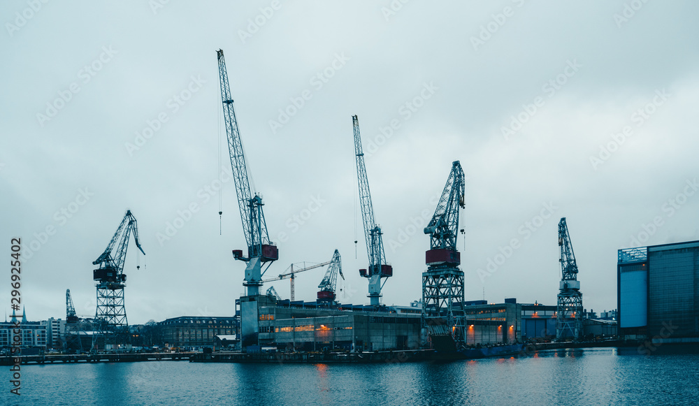 Photo of river, floating cranes, buildings on river bank