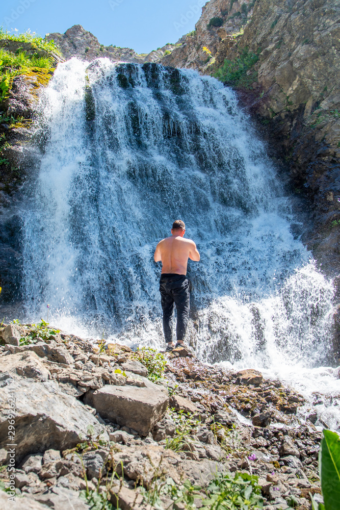A man stands on the background of a waterfall