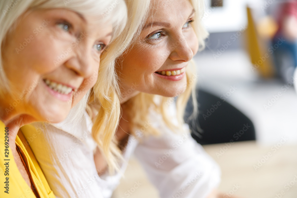 Happy mother and daughter looking away at home Happy mother and daughter looking away at home