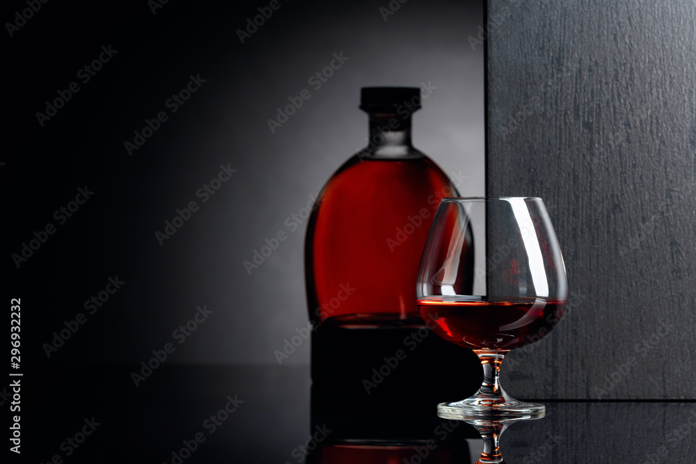 Glass and bottle of brandy on a black reflective background. Glass and bottle of brandy on a black reflective background.