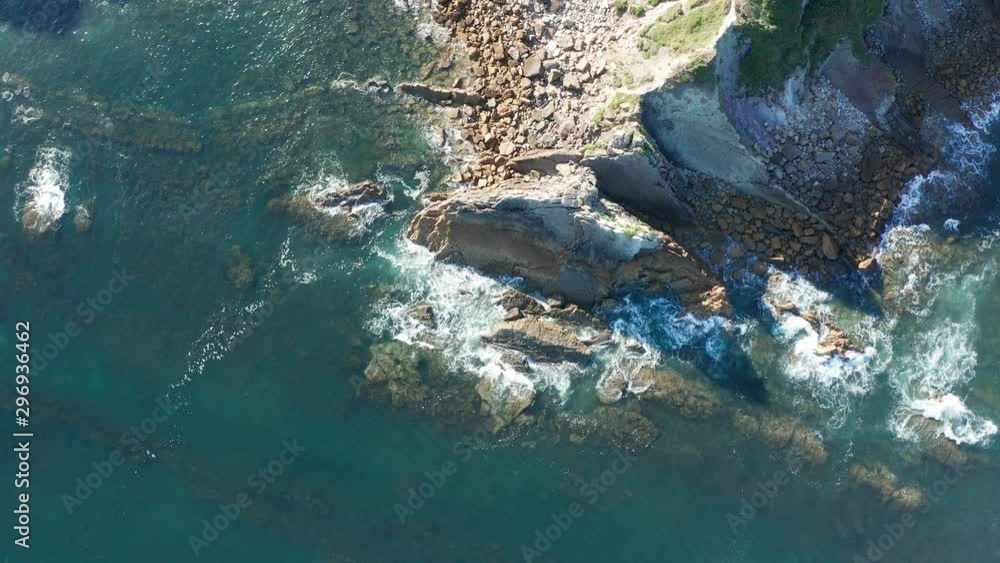 Descending shot over sea waves breaking in the reefs and coast, Cantabrian sea, Spain - drone aerial view Descending shot over sea waves breaking in the reefs and coast, Cantabrian sea, Spain - drone aerial view