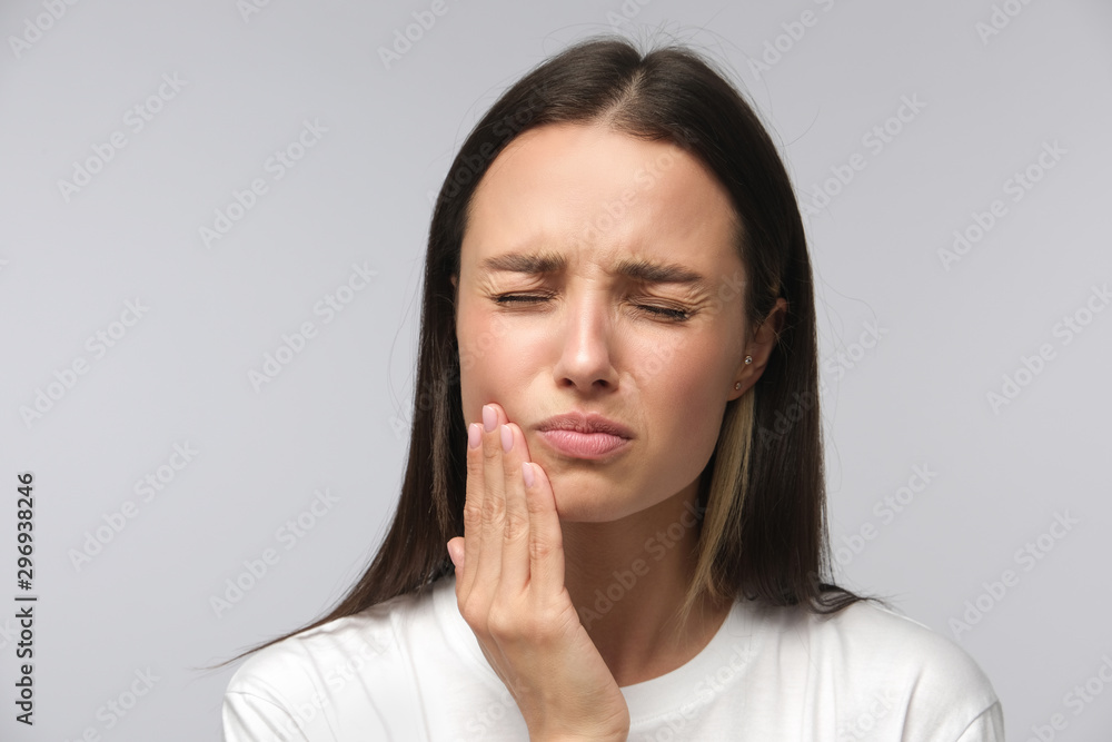 Toothache concept. Studio shot of young female feeling pain, holding her cheek with hand, suffering from bad tooth ache Toothache concept. Studio shot of young female feeling pain, holding her cheek with hand, suffering from bad tooth ache