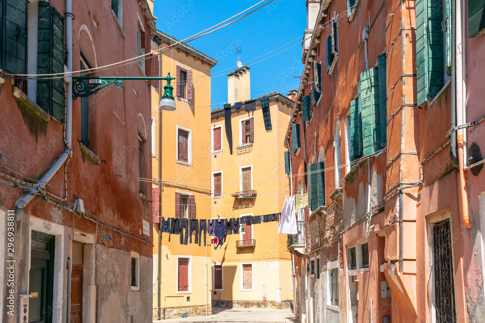 Venice. Colorful laundry is dried on the clotheslines between the houses. Authentic Venetian street in sunshine. Ancient Italian city. Travel Tourism in Europe. 